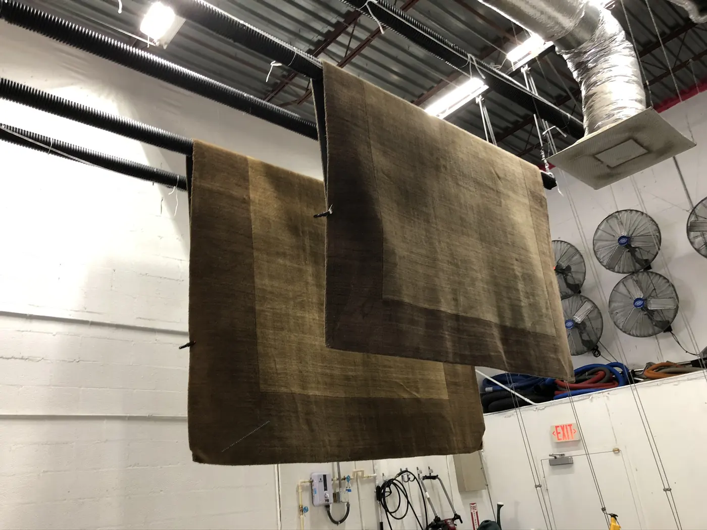 Washed rugs hung from plant racks to dry evenly